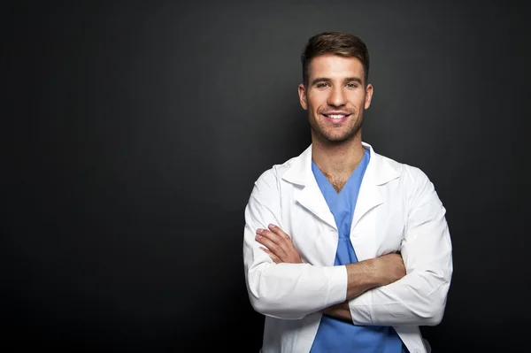 Portrait of confident young medical doctor on dark background — Stock Photo, Image