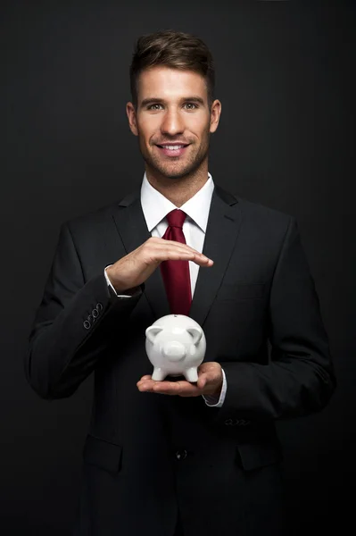 Empresario con alcancía sobre fondo oscuro — Foto de Stock