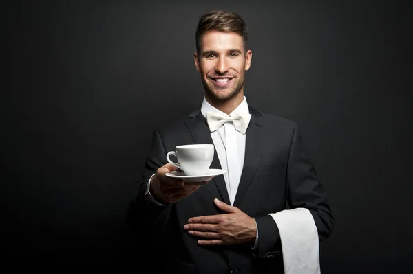 Camarero en traje sosteniendo taza de café —  Fotos de Stock