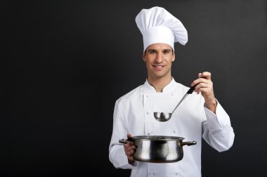 pot ve kaşık tutan koyu arka planı yemek