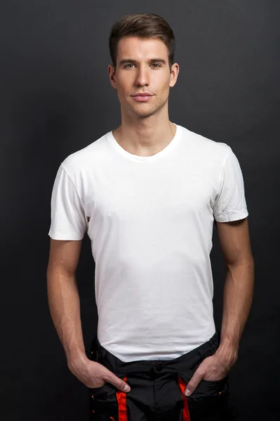 Hombre guapo posando en camiseta blanca sobre fondo oscuro en estudio —  Fotos de Stock