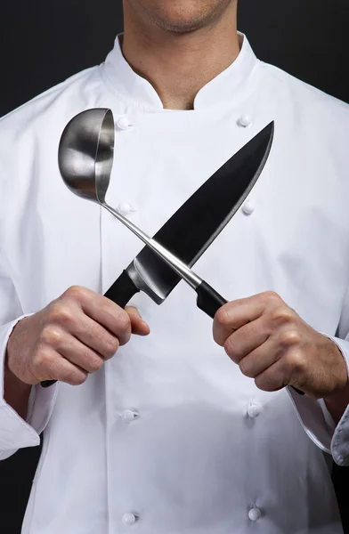 Emotional cook with knife and fork in his hands on grey backgrou — Stock Photo, Image