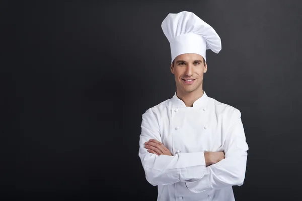 Cozinheiro sorridente contra fundo escuro sorrindo para a câmera — Fotografia de Stock