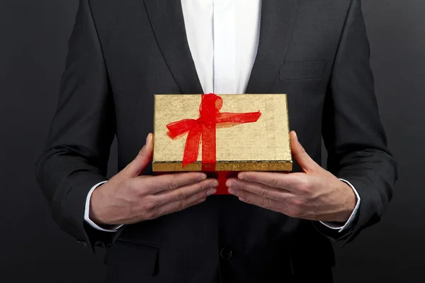 Close up de mãos de homem segurando caixa de presente sobre fundo escuro — Fotografia de Stock