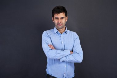 yakışıklı delikanlı crosed kolları olan gri arka plan üzerinde gülümseyen