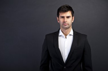 siyah elbiseli koyu arka plan üzerinde gülümseyen yakışıklı delikanlı