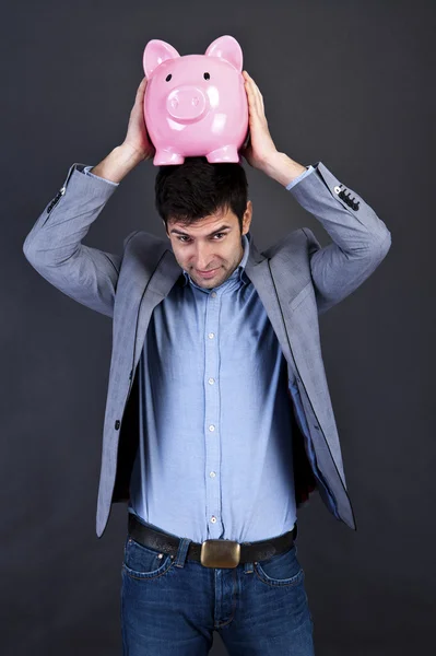 Geschäftsmann mit Sparschwein über dunklem Hintergrund mit Sparschwein oben — Stockfoto