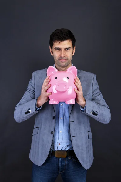 Zakenman met piggy bank over donkere achtergrond — Stockfoto