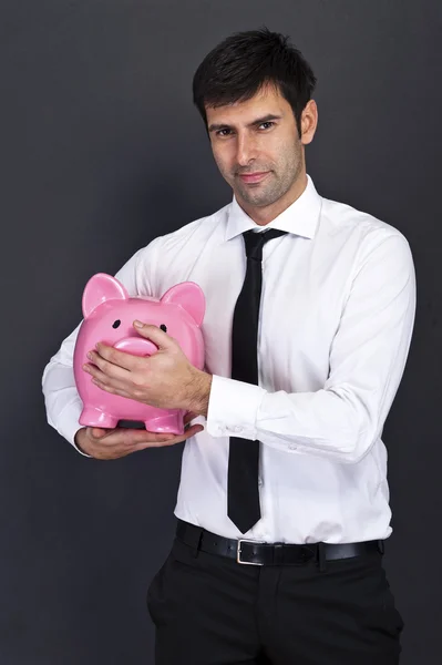 Jovem com banco porquinho (caixa de dinheiro), em fundo escuro — Fotografia de Stock