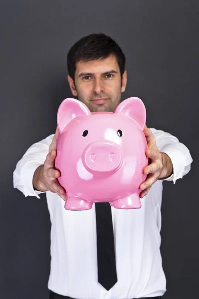 Portrait of young man holding a piggy bank against a grunge back — Stock Photo, Image