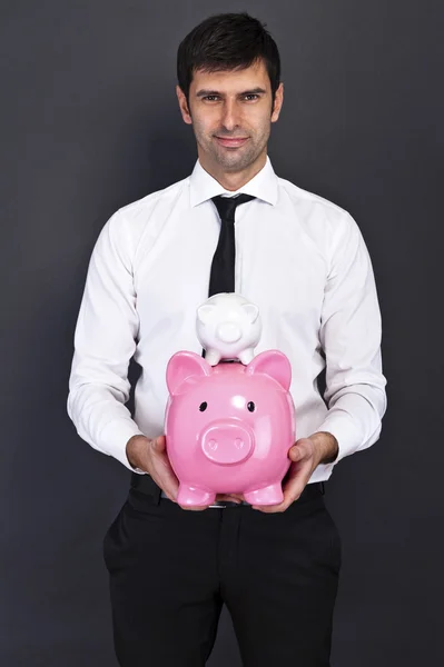 Portrait of young man holding a two piggy bank against a grunge — Stock Photo, Image