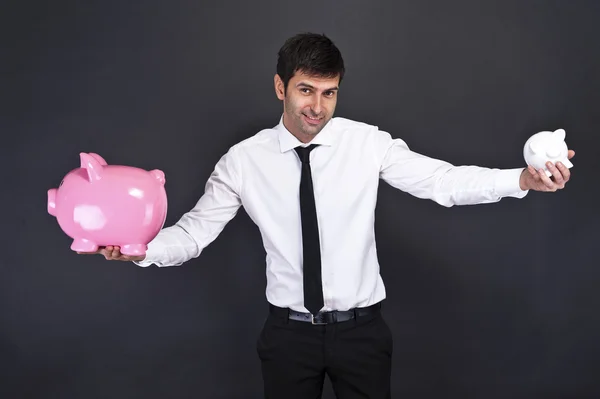 Portrait of young man holding a two piggy bank against a grunge — Stock Photo, Image