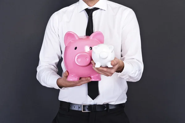 Porträt eines jungen Mannes, der ein Sparschwein gegen einen Grunge hält — Stockfoto
