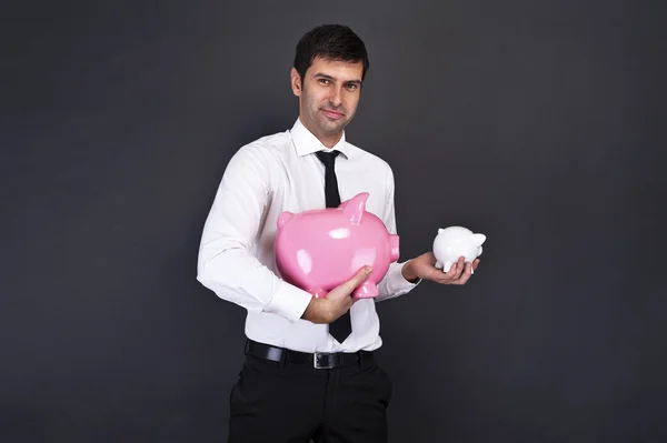 Portrait of young man holding a two piggy bank against a grunge — Stock Photo, Image