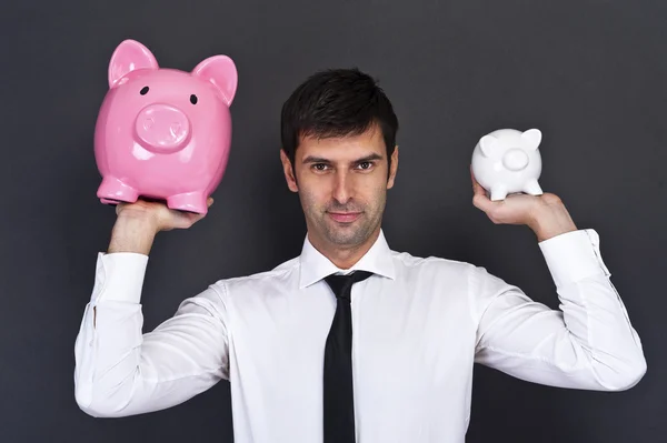 Portrait of young man holding a two piggy bank against a grunge — Stock Photo, Image