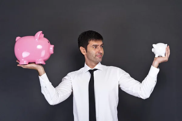 Portrait of young man holding a two piggy bank against a grunge — Stock Photo, Image