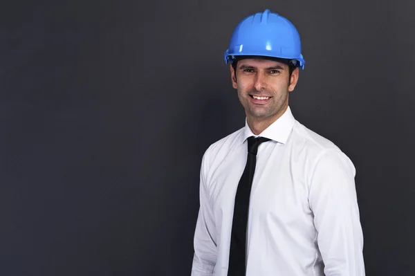 Joven trabajador de la construcción en sombrero duro sobre fondo gris — Foto de Stock