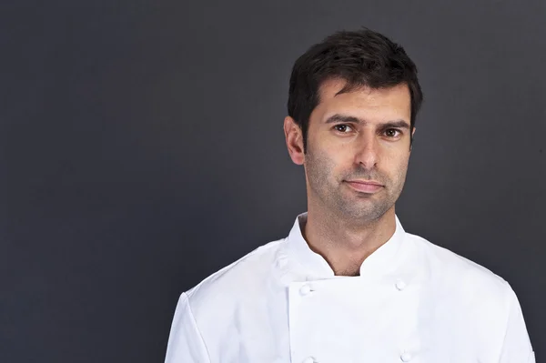 Porträtt av en ung kock man bär uniform innehar en kniv ove — Stockfoto