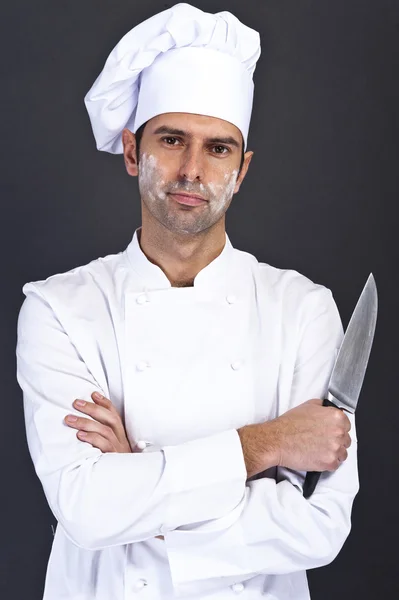 Portrait of a young cook man wearing uniform holding a knife ove — Stock Photo, Image