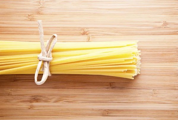 Bundle of Italian spaghetti pasta tied with string lying on old — Stockfoto