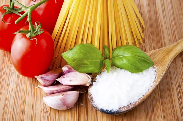 Whole wheat spaghetti and vegetables on wooden tabletop — Stock Photo, Image