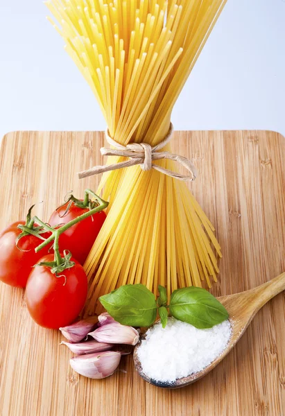 Whole wheat spaghetti and vegetables on wooden tabletop — Stock Photo, Image