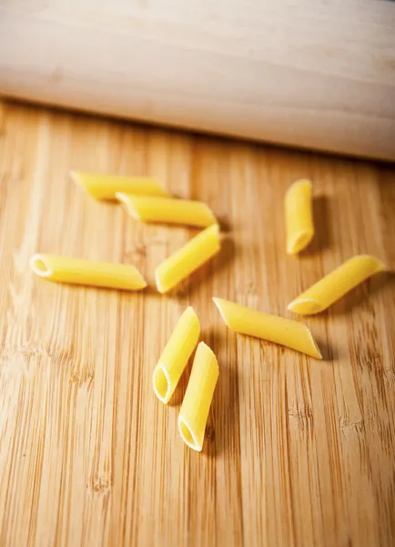 Pasta de penne cruda sobre fondo de madera —  Fotos de Stock