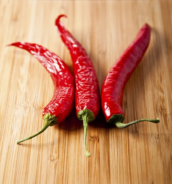 Red hot chilli papričky na starém dřevěném stole — Stock fotografie