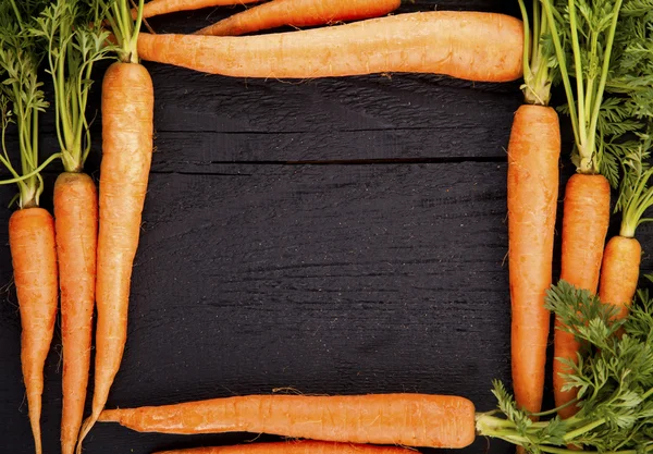 Mazzo di carote fresche con foglie verdi su sfondo di legno . — Foto Stock