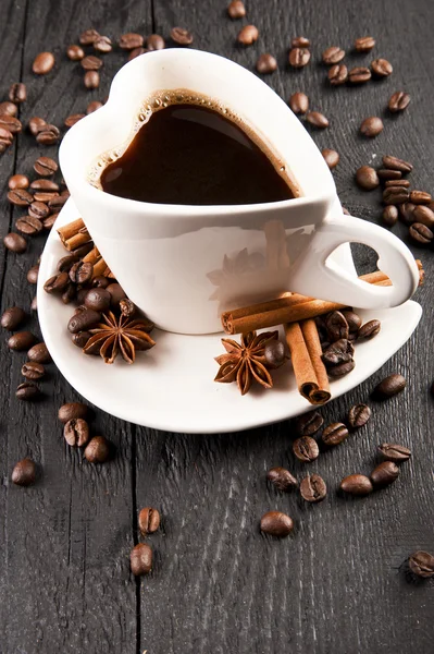 Tasse de café en forme de coeur et grains de café sur fond sombre — Photo