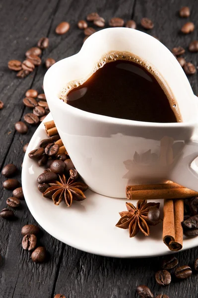 Šálek kávy ve tvaru srdce a kávová zrna na tmavém pozadí — Stock fotografie