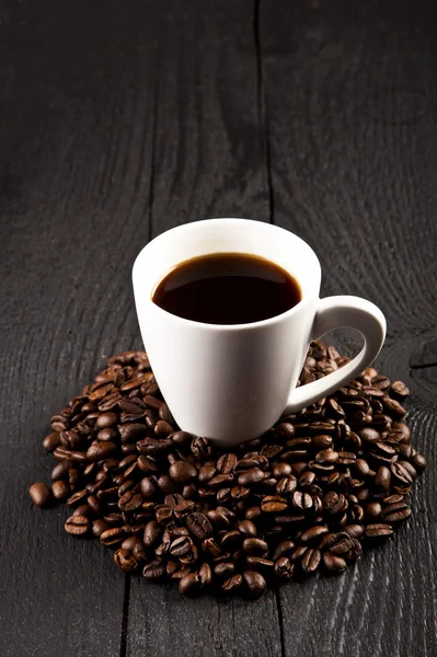 Kopp kaffe och kaffebönor över mörk bakgrund — Stockfoto
