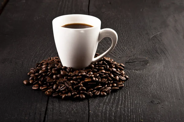 Kopp kaffe och kaffebönor över mörk bakgrund — Stockfoto