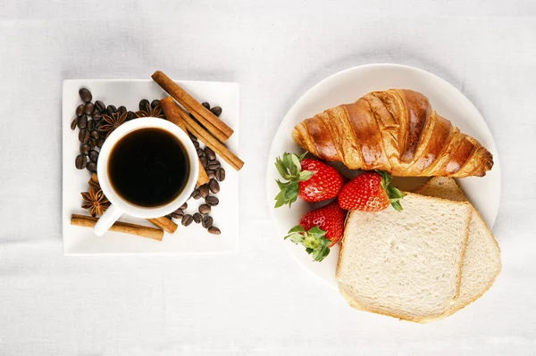 Snídaně s kávou a croissanty v košíku na stole — Stock fotografie