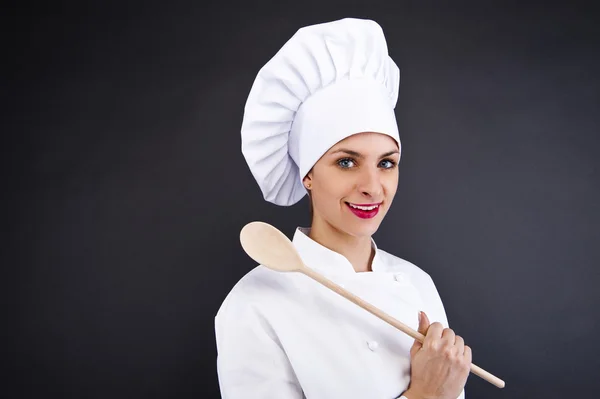 Retrato de mujer joven chef con cuchara sobre fondo oscuro — Foto de Stock