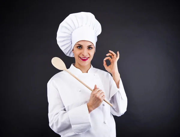 Portrait of young woman chef with spoon on dark background — Stock Photo, Image