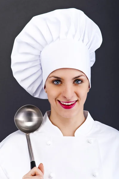 Portrait of young woman chef with spoon on dark background — Stock Photo, Image