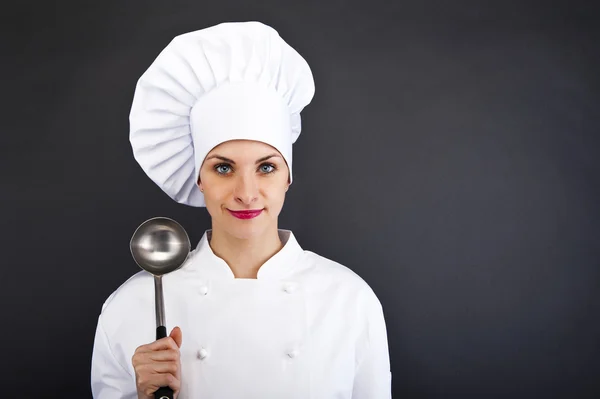 Portrait de jeune femme chef avec cuillère sur fond sombre — Photo