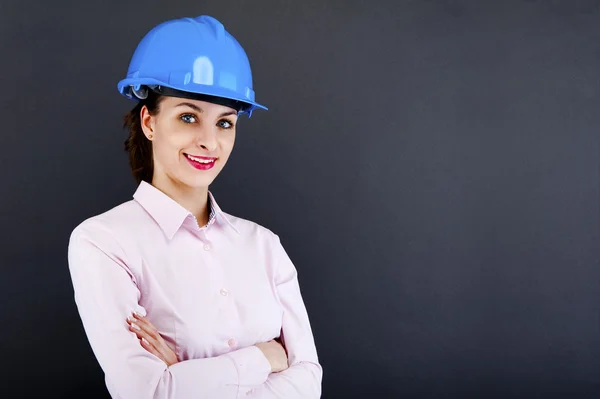 Mujer arquitecta, contratista en casco azul sobre fondo oscuro — Foto de Stock