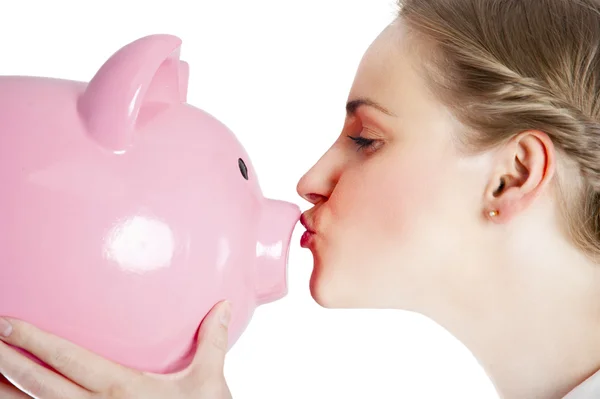 Blond young woman kissing a piggy bank with her lips — Stock Photo, Image