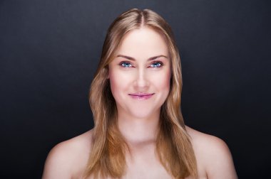 sarışın bir kadın gülümseyerek koyu arka plan üzerinde