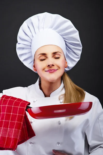 Mujer joven chef con diferentes herramientas sobre fondo oscuro — Foto de Stock