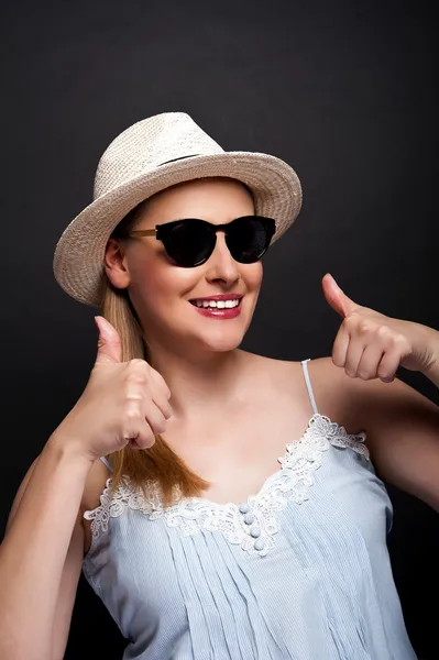 Mujer en sombrero y gafas de sol mostrando ok pulgares sobre oscuro banckgro —  Fotos de Stock