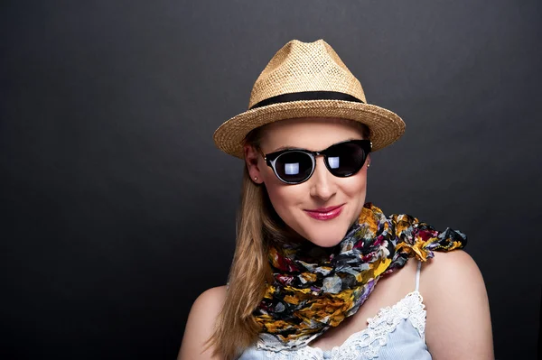 Женщина в шляпе и солнцезащитных очках на темном фоне — стоковое фото