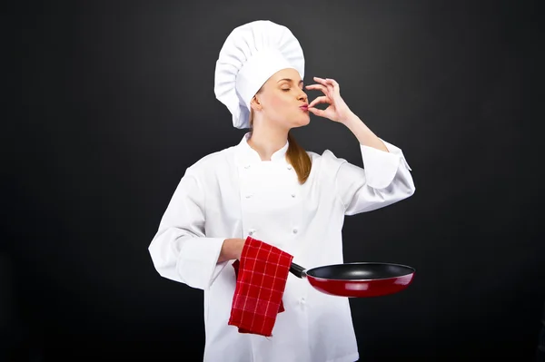 Young female chef kissing her hand to show perfection over dark — Stock Photo, Image