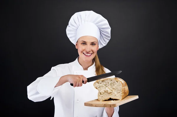 Kocken baker smailing, nybakat bröd. — Stockfoto