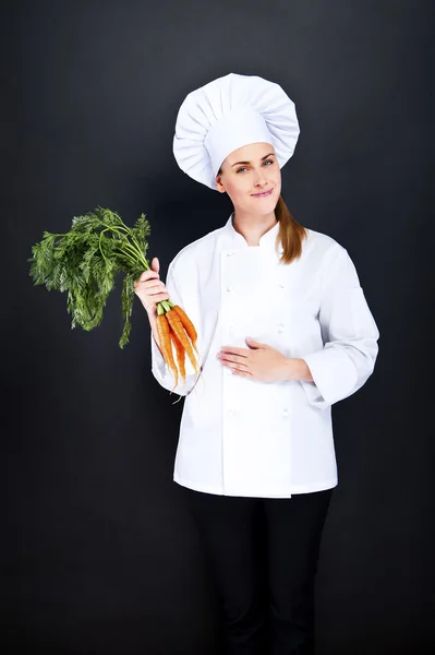 Kvinnliga kock i vit uniform med massa morötter — Stockfoto