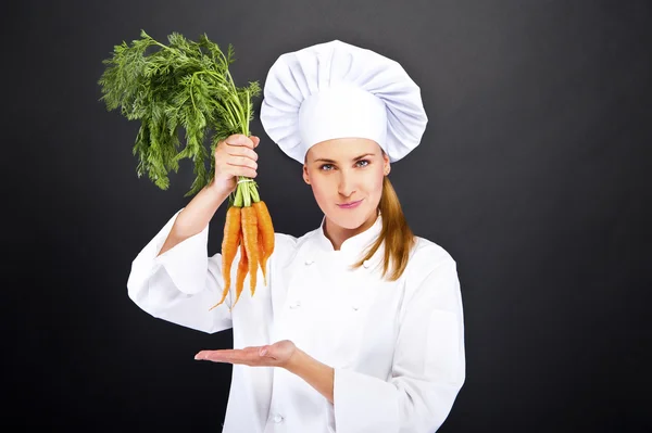 Kobieta kucharz w białym mundurze pęczek marchewki — Zdjęcie stockowe