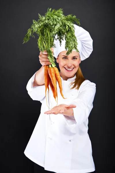 Vrouwelijke cook in wit pak met bos van wortelen — Stockfoto