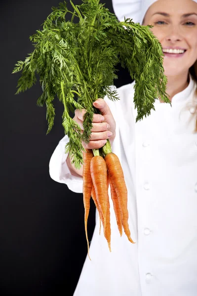 Cocinera en uniforme blanco con racimo de zanahorias —  Fotos de Stock